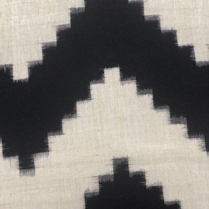 May include: Black and white ikat fabric with a geometric pattern. The fabric has a subtle sheen and a soft texture.