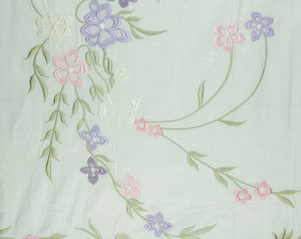May include: A light blue fabric with embroidered flowers in shades of pink, purple, and white. The flowers are arranged in a delicate pattern on the fabric.
