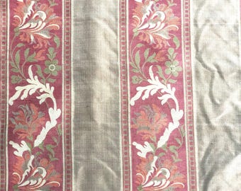 May include: Beige fabric with vertical stripes of a floral pattern in shades of red, pink, white, and green.
