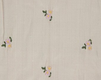May include: A close-up of a light beige fabric with a subtle floral pattern. The fabric is embroidered with small pink and yellow flowers.