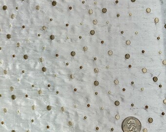 May include: White fabric with a subtle shimmer, featuring a scattered pattern of small, embroidered circles in shades of gold and brown.