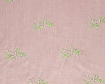May include: A pale pink fabric with a repeating pattern of small white flowers and green leaves.