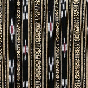May include: Close-up of a black fabric with a repeating pattern of vertical stripes. The stripes alternate between gold, white, and black. The design includes geometric shapes and red accents. A quarter coin is in the bottom right corner.