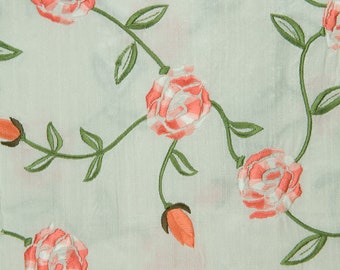 May include: White fabric with a delicate floral pattern. The fabric features pink and white roses with green leaves and stems.
