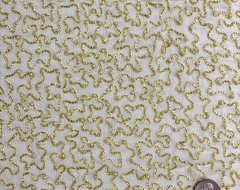 May include: White fabric with a gold embroidered pattern of small, irregular shapes. The fabric is decorated with small white beads.