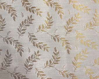 May include: White fabric with a gold leaf pattern. The fabric has a subtle texture and a slightly shiny finish.