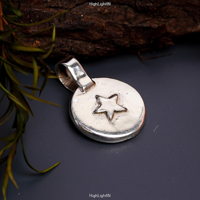 May include: A silver pendant with a star design. The pendant is round and has a loop at the top for attaching to a chain.
