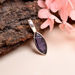 May include: A silver pendant with a marquise-shaped amethyst gemstone. The pendant is set in a simple, elegant design.