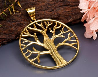 May include: Gold-toned metal pendant featuring a tree of life design. The pendant is circular and has a detailed, intricate design of a tree with branches and leaves.