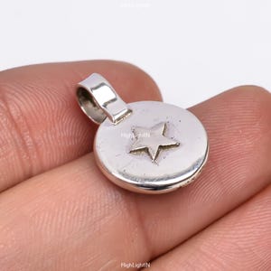 Può includere: Ciondolo pendente in argento con un design a stella. Il ciondolo è rotondo e ha un anello nella parte superiore per attaccarlo a una catena o un braccialetto.
