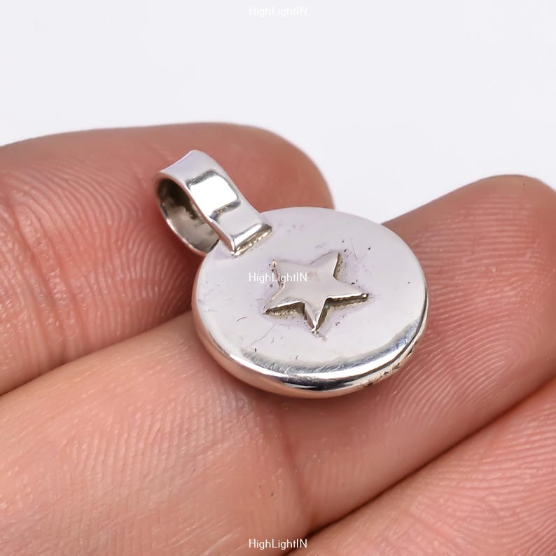May include: Silver pendant charm with a star design. The pendant is round and has a loop at the top for attaching to a chain or bracelet.