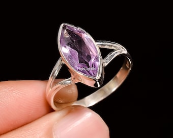 May include: A silver ring with a marquise-shaped amethyst gemstone. The ring has a delicate, twisted band.