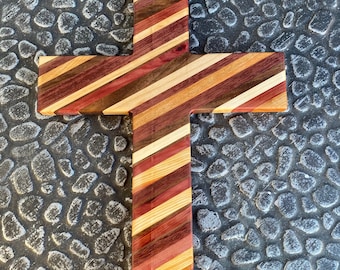 May include: A wooden cross made of various types of wood, including cedar, walnut, and maple. The wood is arranged in a striped pattern, creating a unique and beautiful design.