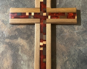 May include: A wooden cross with a red, brown, and beige inlay design. The cross is made of multiple pieces of wood that are joined together to create a mosaic pattern.