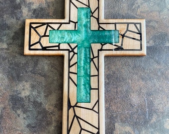 May include: A wooden cross with a stained glass design. The glass is a vibrant green color and is set into the wood. The cross is a great addition to any home decor.