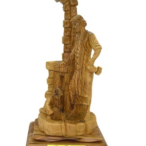 May include: A hand-carved wooden statue of Saint Joseph, the patron saint of carpenters, holding a hammer and chisel. The statue is made of olive wood and features intricate details. The base of the statue is inscribed with the words "St. Joseph".