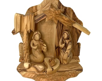 Può includere: Un presepe in legno intagliato a mano con una stella, una mangiatoia e figure di Maria e Giuseppe. La scena è realizzata in legno d'ulivo e ha una finitura naturale e rustica.