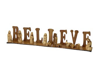 May include: Wooden BELIEVE sign with a nativity scene set in front of it. The set includes figures of Mary, Joseph, baby Jesus, a shepherd, a donkey, a sheep, and an angel.