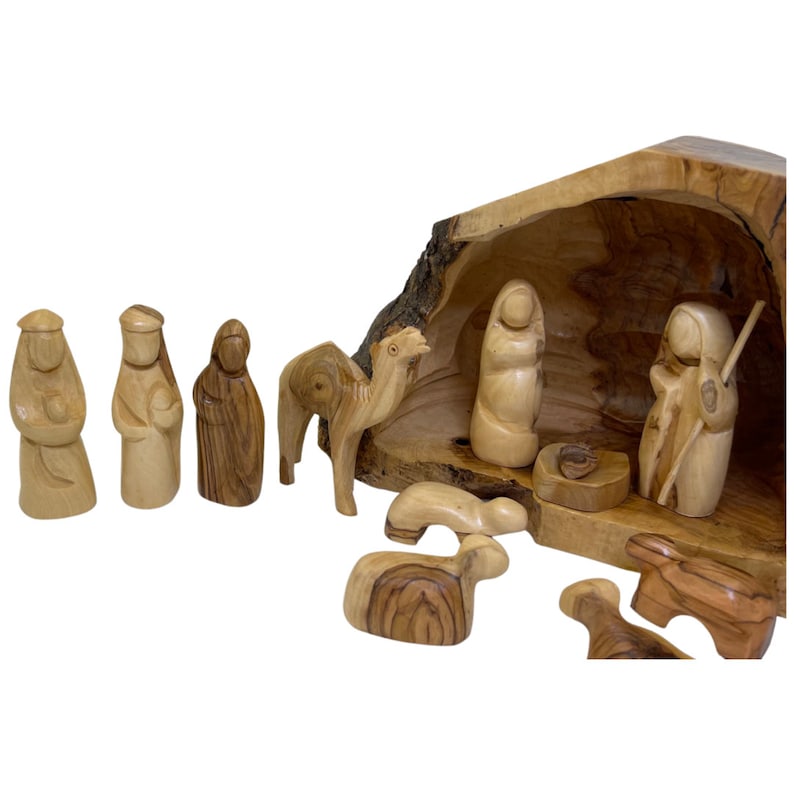 May include: A wooden nativity scene set with a carved olive wood manger, figures of Mary, Joseph, baby Jesus, a camel, a shepherd, and sheep. The set is made of natural wood and has a rustic, handcrafted look.