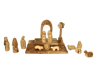 May include: A wooden nativity scene set with a carved archway, a palm tree, Mary, Joseph, baby Jesus, and three shepherds. The set also includes three sheep and a wooden base.