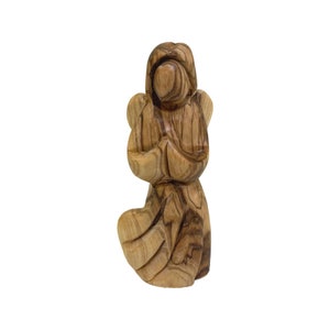 May include: A hand-carved wooden angel figurine with intricate details. The angel is kneeling with its hands clasped in prayer. The wood is a rich brown colour with natural grain patterns.