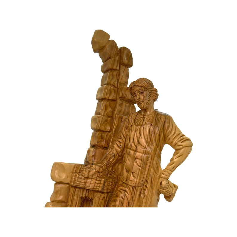 May include: A hand-carved wooden sculpture of a man carrying a large wooden beam on his shoulder. The sculpture is made of olive wood and has a natural, rustic finish.