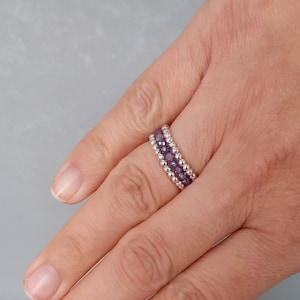 May include: A silver ring with three rows of purple beads.