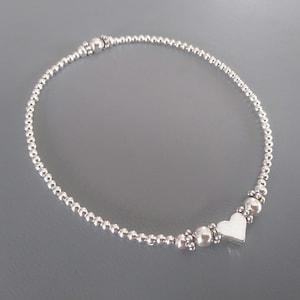 May include: A silver beaded anklet with a heart charm.