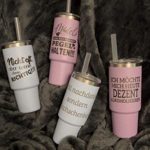 Könnte beinhalten: Vier Edelstahlbecher mit Deckel und Strohhalm, jeder mit einem anderen deutschen Satz in silberner Schrift. Zwei sind weiß, zwei sind rosa. Die Sätze lauten "Nicht oft, aber wenn dann RICHTIG!!!" und "Mädels, EGAL WAS PASSIERT, PEGEL HALTEN!!!".