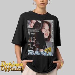 K&ouml;nnte beinhalten: Schwarzes T-Shirt mit einem Grafikdruck einer Frau mit einem Schwarzwei&szlig;bild eines Frauen Gesichts mit dem Text "PG-13 SANA MINATOZAKI" und "SANA" in silberner Schrift.