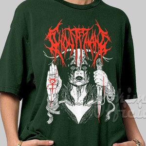 May include: A dark green t-shirt with a white and red graphic print of a woman with a skull mask and a knife. The text "GHOSTFACE" is printed in red above the woman.
