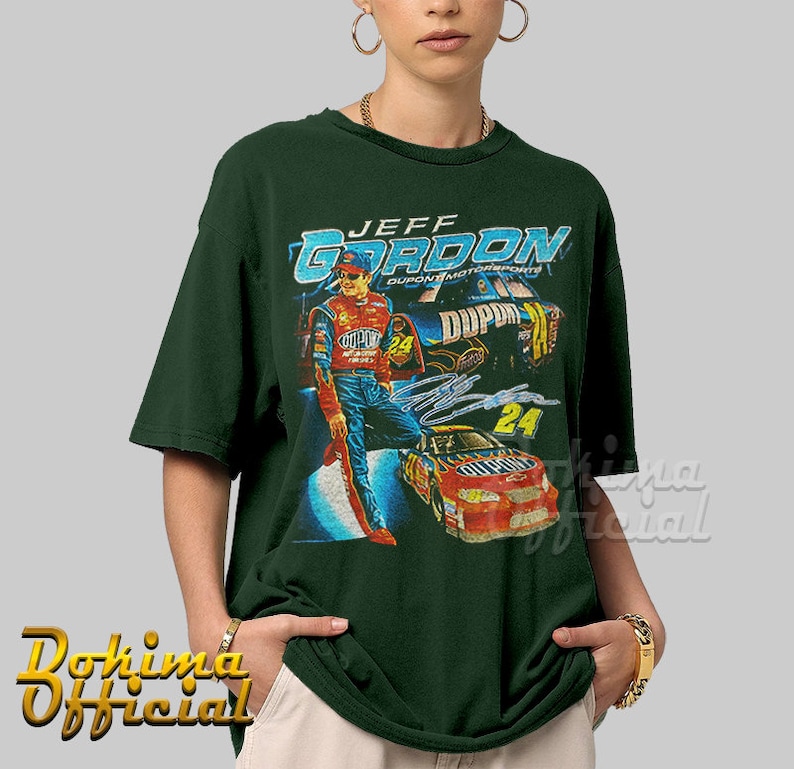 May include: A green t-shirt with a vintage-style graphic of Jeff Gordon, a NASCAR driver, in his race car. The graphic features the text "Jeff Gordon" and "Dupont Motorsports".