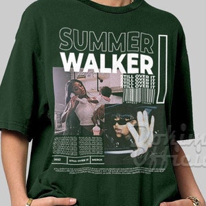 May include: A dark green t-shirt with a white graphic print of Summer Walker. The graphic includes a photo of Summer Walker and the text "Summer Walker" and "Still Over It".