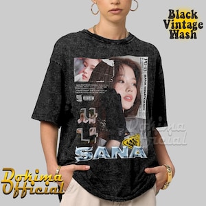 K&ouml;nnte beinhalten: Ein schwarzes Vintage-T-Shirt mit Wasch-Effekt und einem Grafikdruck mit dem Gesicht einer Frau und dem Text "SANA" in einer verwaschenen Schriftart. Die Grafik enth&auml;lt auch den Text "PG-13 SANA MINATOZAKI" und einen "BAD VIBES" Aufkleber.