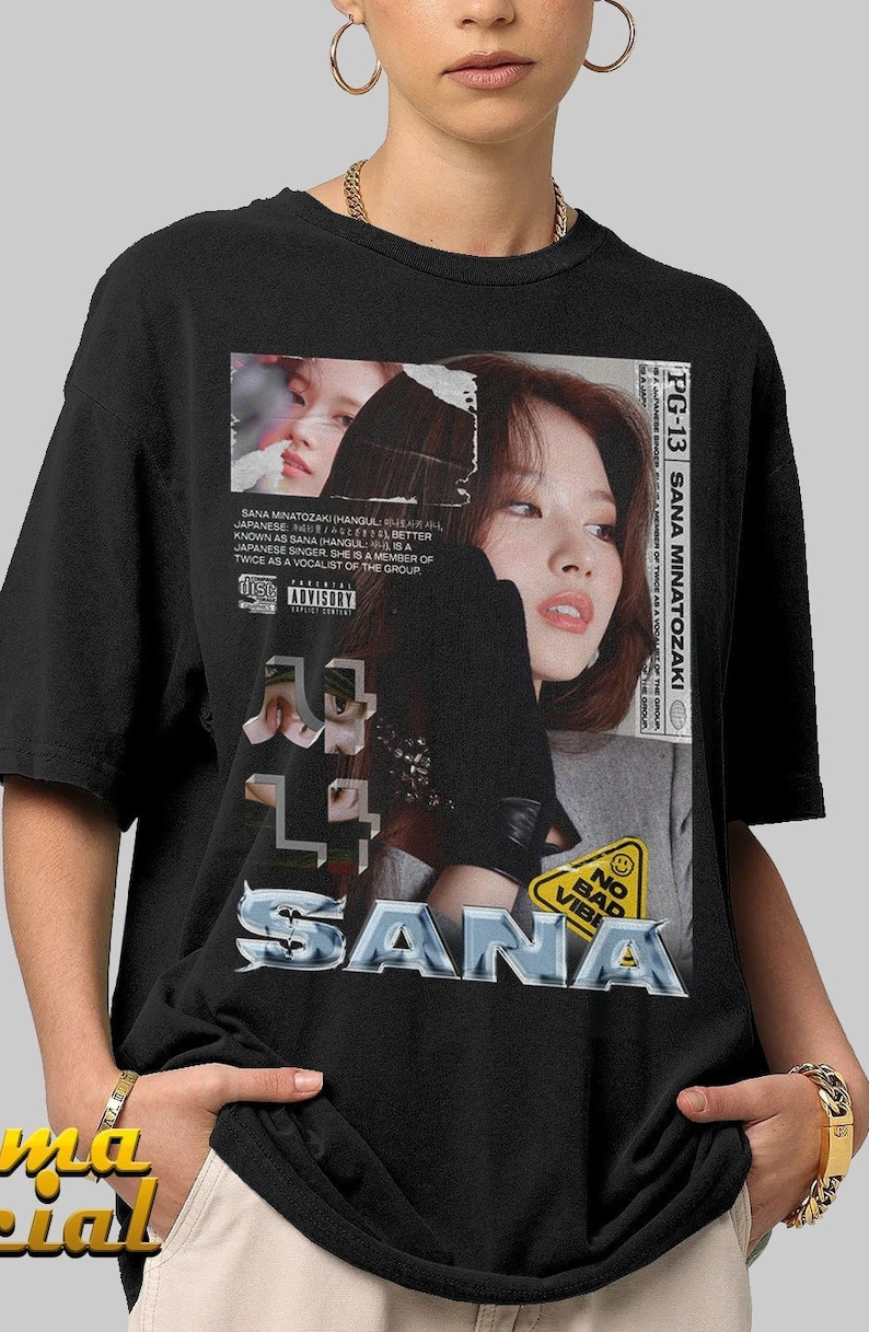 K&ouml;nnte beinhalten: Ein schwarzes T-Shirt mit einem Grafikdruck eines Frauen Gesichts und dem Wort "SANA" in silberner, glitzernder Schrift. Die Grafik enth&auml;lt auch ein gelbes Warnschild mit dem Text "NO BAD VIBE".