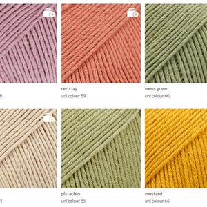 May include: A collection of six skeins of yarn in various colors. The colors include amethyst, red clay, moss green, light beige, pistachio, and mustard. Each skein is labeled with its color name and a unique number.