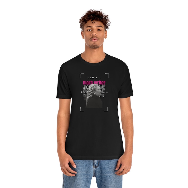 Peut inclure: Un t-shirt noir avec un motif graphique repr&eacute;sentant le visage d'une femme et le texte "I am a... black writer" en rose et noir.
