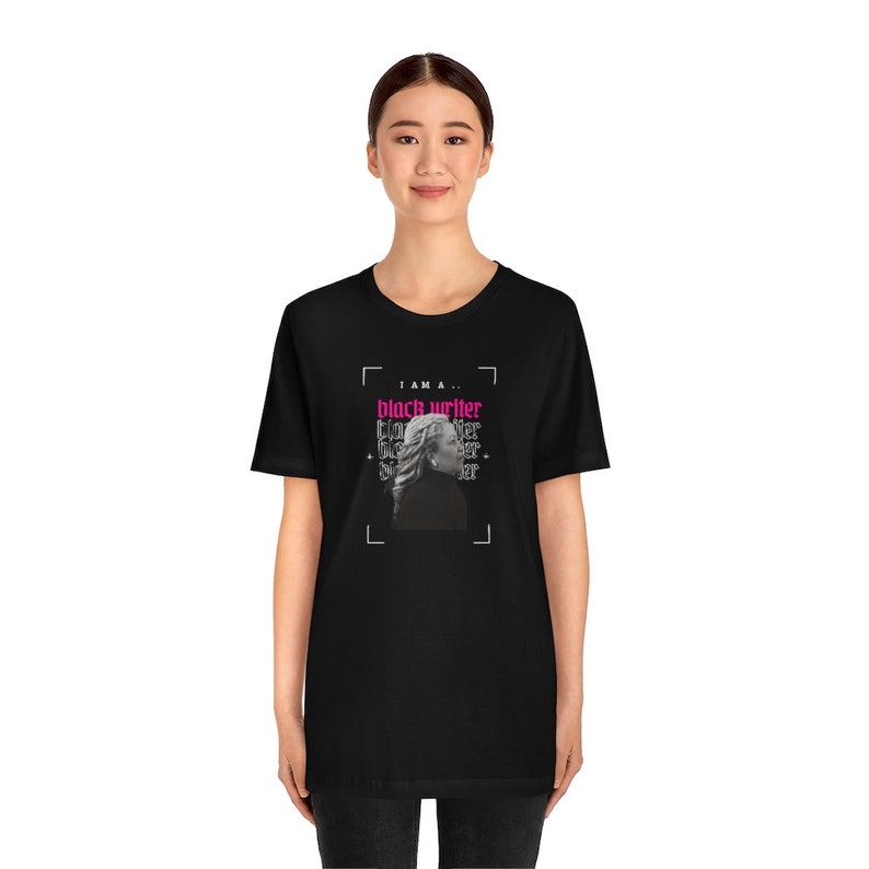 Peut inclure: T-shirt noir avec un imprim&eacute; graphique d'un visage de femme et le texte "I am a... black writer" en rose.