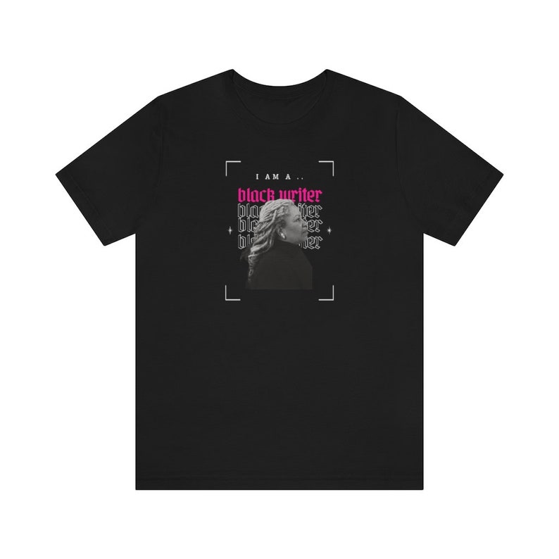 Peut inclure: T-shirt noir avec un graphique d'un visage de femme et le texte "Je suis un... &eacute;crivain noir" en rose.