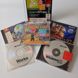 May include: A collection of vintage software CD-ROMs including QuarkXPress 5, Greeting Card for Windows 3.1 & 95, Microsoft Encarta 97, Microsoft Works, and Microsoft Windows 95 Upgrade. Each disc is housed in its original plastic jewel case.