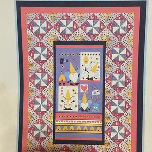May include: A quilt kit featuring a design of honey bee gnomes with a twirling quilt pattern. The kit includes fabric for a 58 inch by 85 inch quilt.