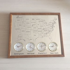 Wandklok met 4 zones en kaart met meerdere zones van Amerika. Kaarten en plaatsnamen zijn in de spiegel gegraveerd. Gepersonaliseerde klokken in de Amerikaanse zone.Voor aan de muur