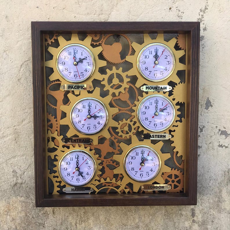 May include: A wooden framed wall clock with six smaller clocks inside, each representing a different time zone. The clocks are surrounded by gold gears and the time zones are labeled: Pacific, Mountain, Central, Eastern, Hawaii, and London.