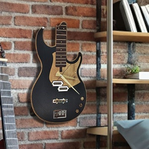 Op de afbeelding: Een zwarte en bruine elektrische basgitaar klok met een houtnerf afwerking. De wijzerplaat bevindt zich op het lichaam van de gitaar en heeft gouden wijzers.
