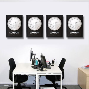 Puede incluir: Cuatro relojes de marco negro con caras blancas y manecillas negras. Cada reloj tiene la palabra "LONDON" impresa debajo de la cara. Los relojes están colgados en una pared blanca sobre un escritorio blanco con dos sillas de oficina negras.
