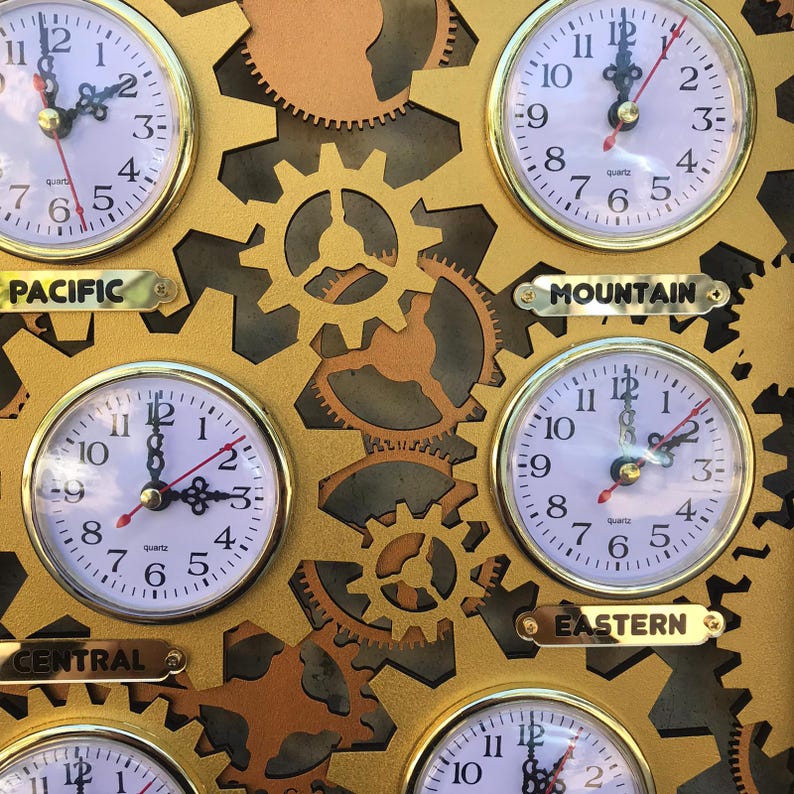 May include: A gold-colored wall clock with four round analog clocks displaying different time zones. The clocks are labeled "Pacific", "Mountain", "Central", and "Eastern".