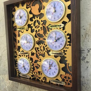 May include: A wooden wall clock with six round analog clocks, each with a different time zone label: Pacific, Mountain, Central, Eastern, Hawaii, and London. The clocks are surrounded by gold gears.