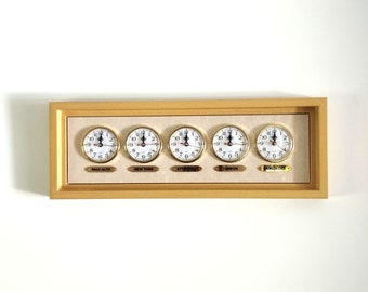 May include: A wooden framed world clock with five analog clocks displaying the time in Palo Alto, New York, Stuttgart, London, and Bangkok.