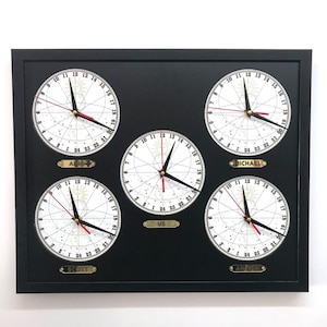 Puede incluir: Un reloj de pared negro enmarcado con cuatro esferas blancas. Cada esfera tiene un nombre diferente: Scott, US, Michael y Amy. Las esferas están divididas en 24 horas y tienen una aguja horaria negra, una aguja minutera roja y una aguja segundera dorada.