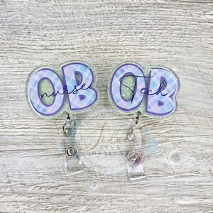 May include: Two OB nurse tech badge reels. Each badge reel has a light blue and purple plaid design with the words "nurse" and "tech" in cursive. The badge reels are attached to a clear plastic retractable reel.